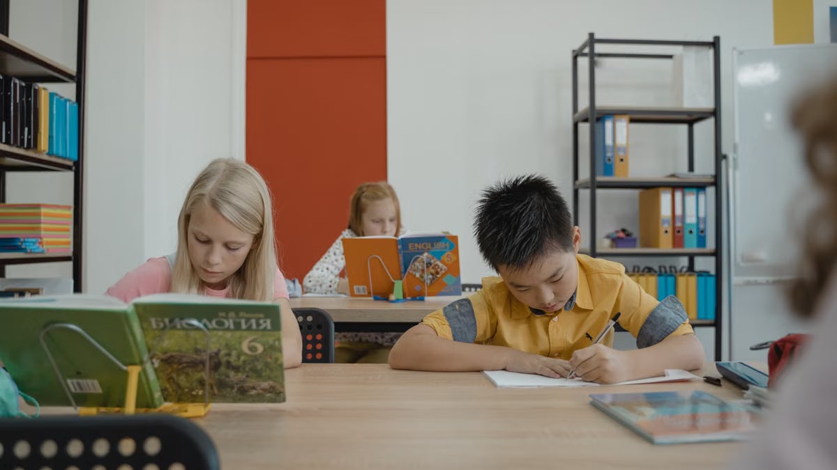 Students of different ethnicities focusing on studies in classroom, surrounded by books and notes.